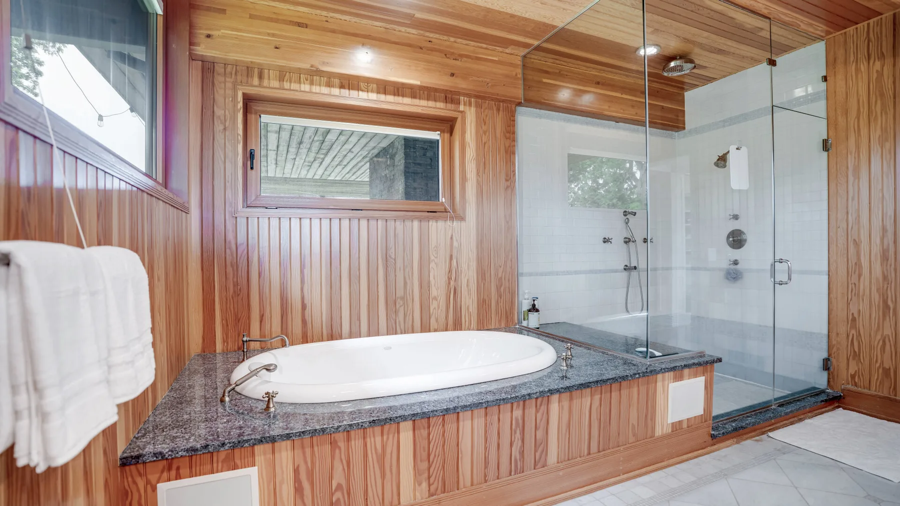 A wood-paneled bathroom with a bathtub and glass shower.
