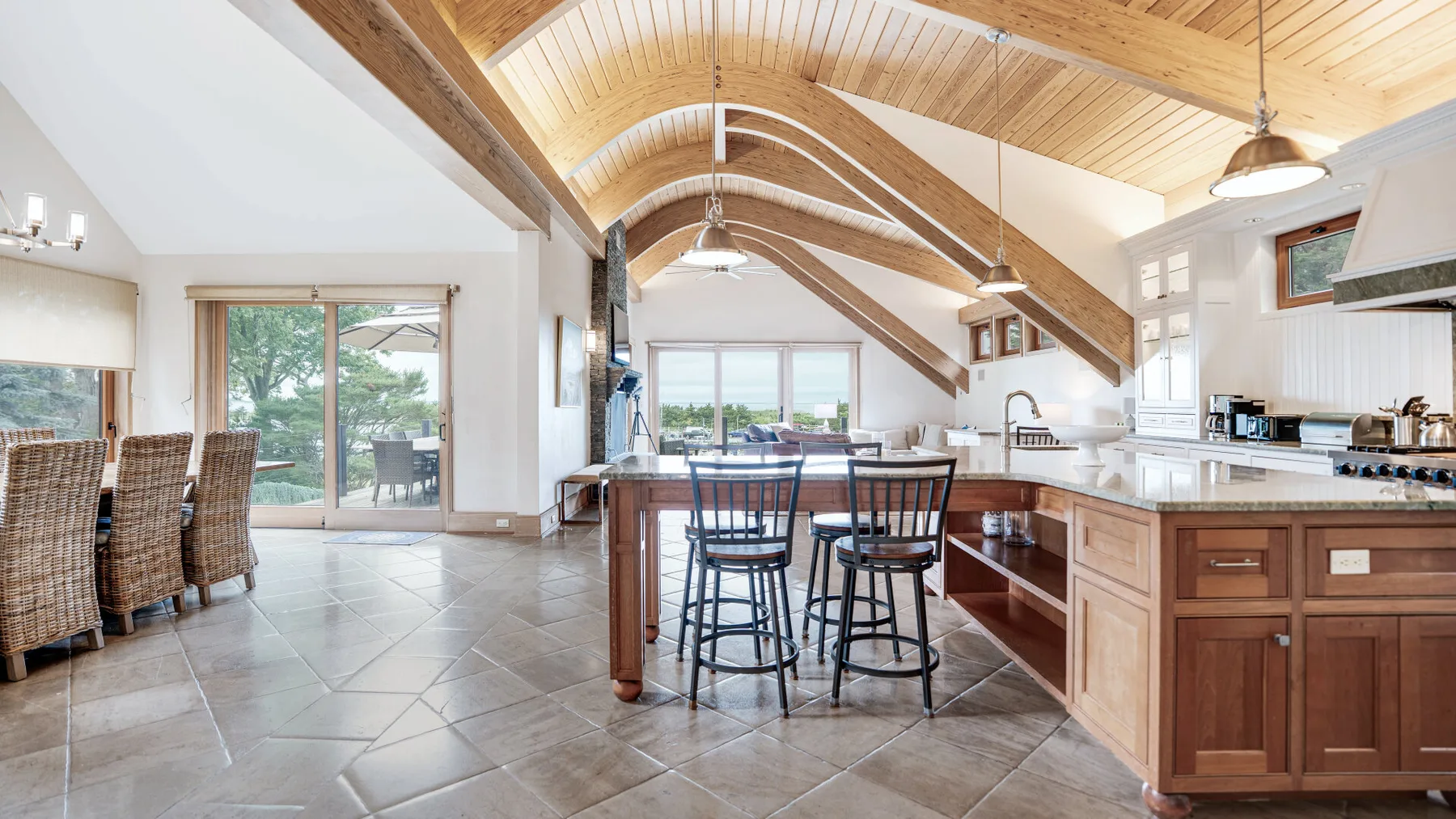 A spacious kitchen and dining area with a wood-paneled vaulted ceiling and large windows.