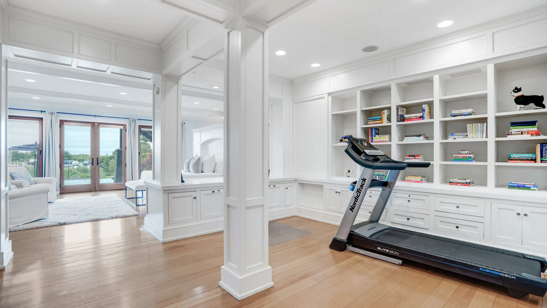 A bright home gym with a treadmill beside built-in shelves.