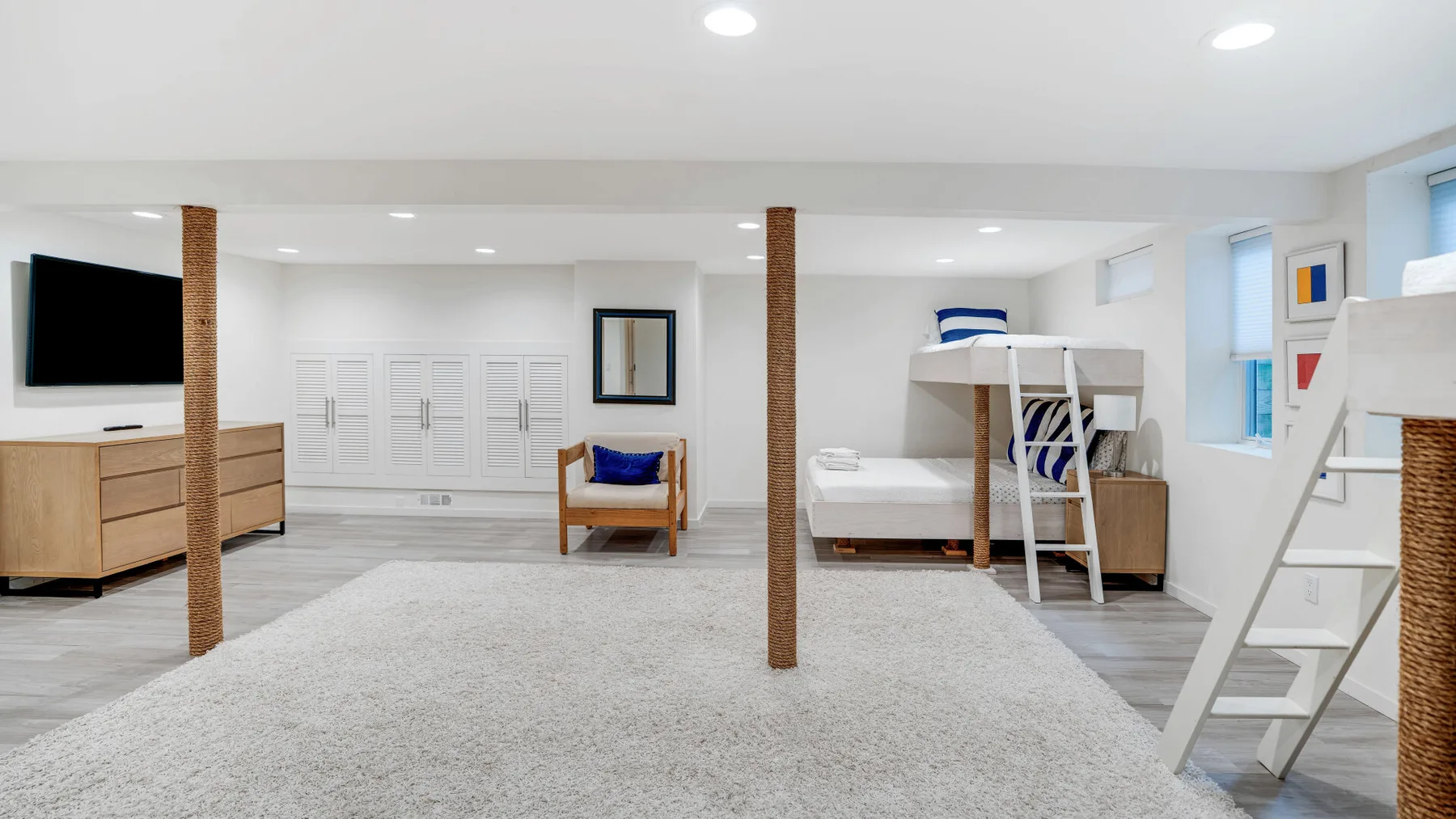 A bright bedroom with white bedding, a loft bed, and a large area rug.