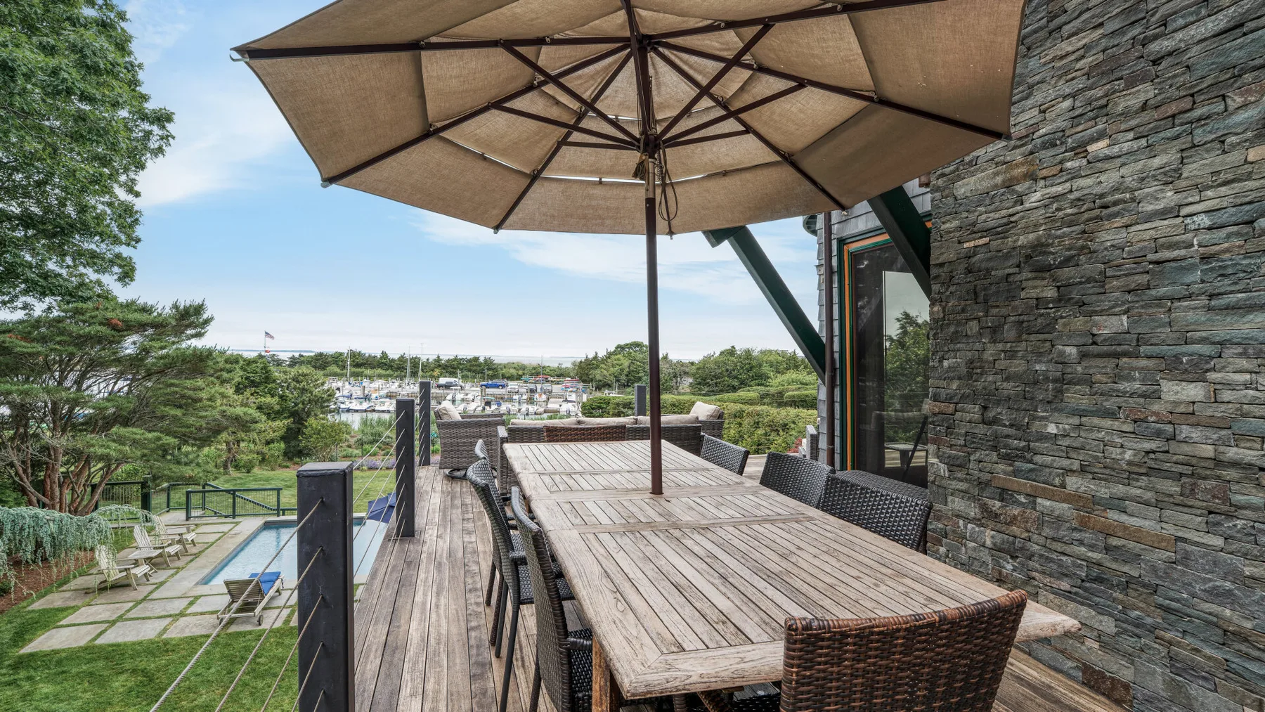 An outdoor dining terrace with a long table beneath a large umbrella.