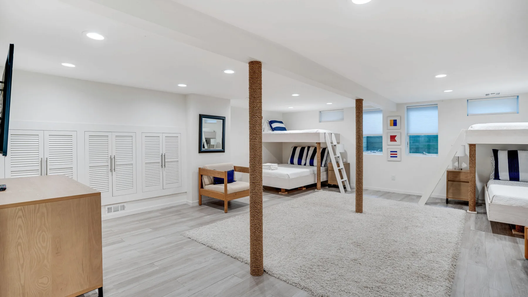 A bright bedroom with raised beds, white walls, and a large rug.