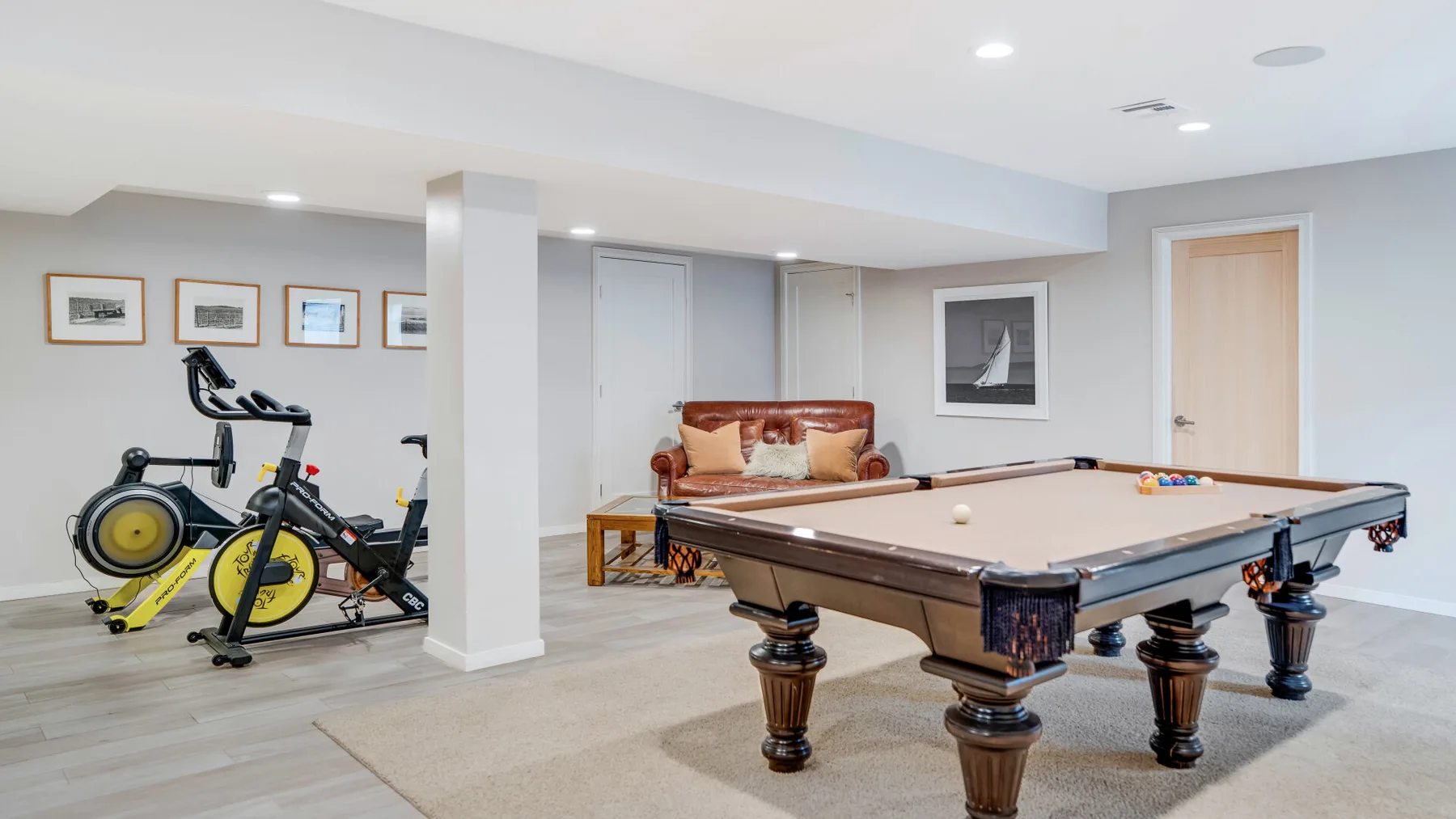 A basement game room with a pool table and exercise equipment.