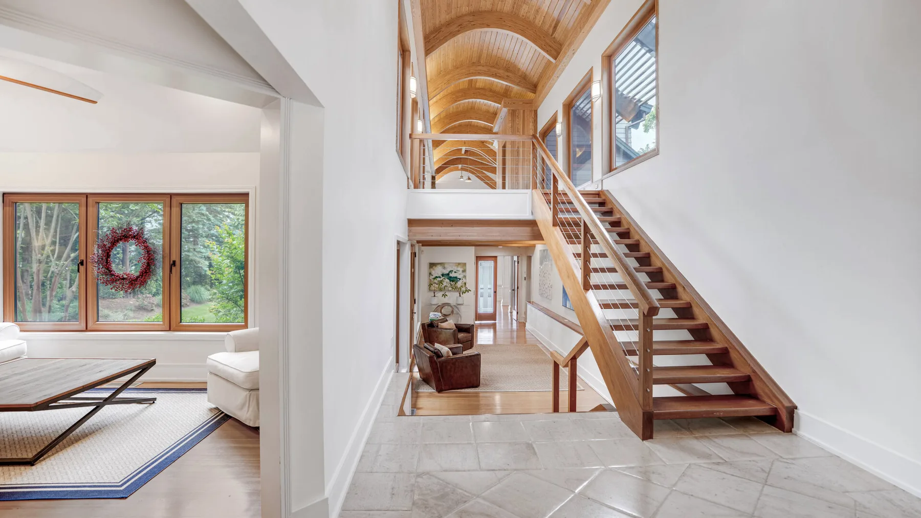 A bright interior hallway features a staircase beneath an arched wooden ceiling.