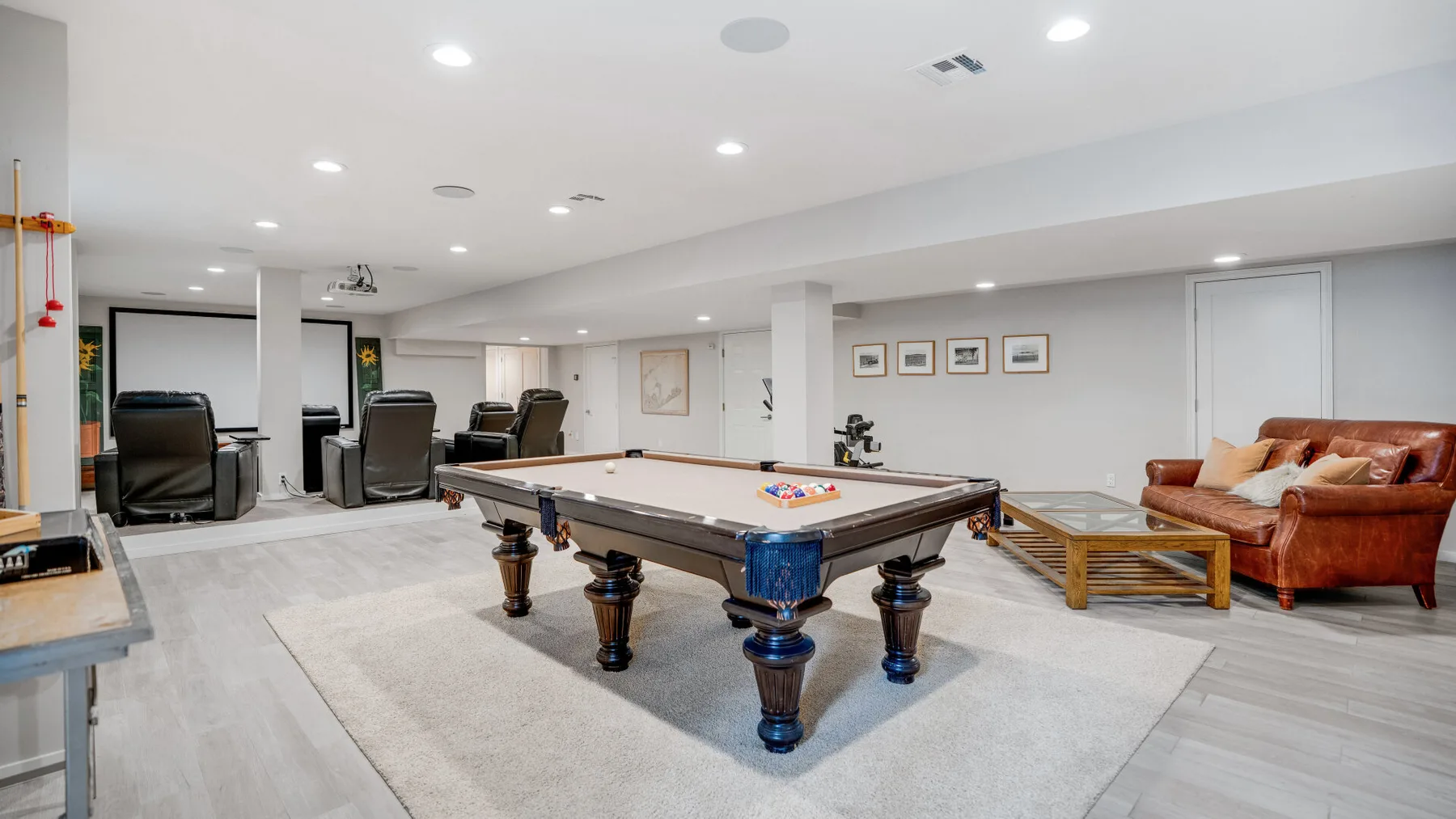 A recreation room with a pool table, seating, and framed wall art.