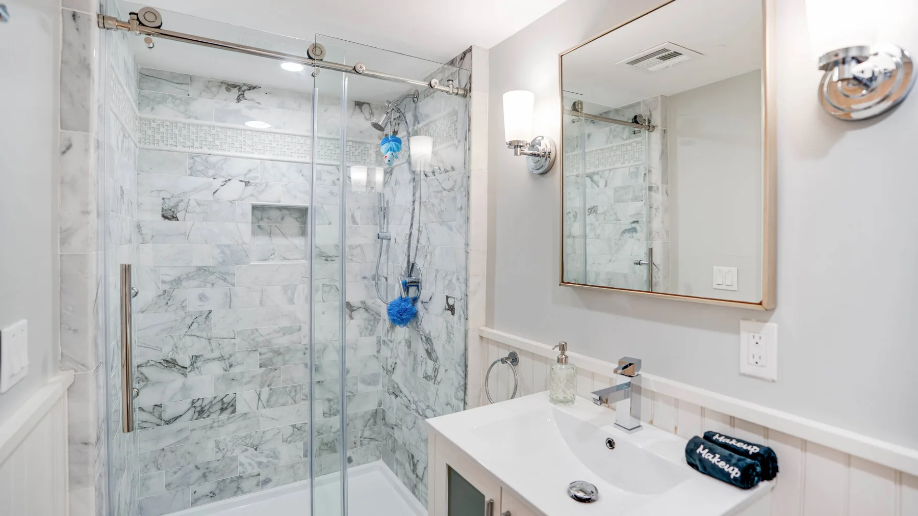 A bright bathroom with a glass shower and a white vanity.