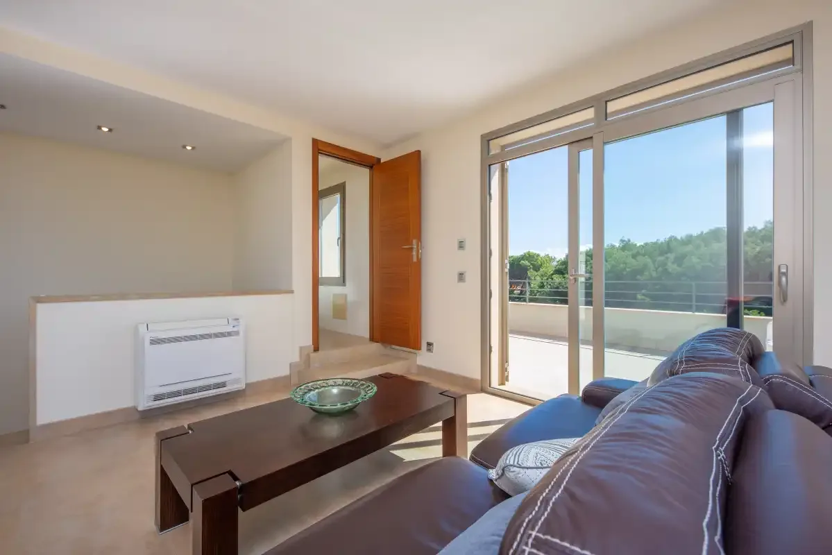 Una sala de estar con asientos, una mesa de centro y puertas de vidrio hacia un balcón.