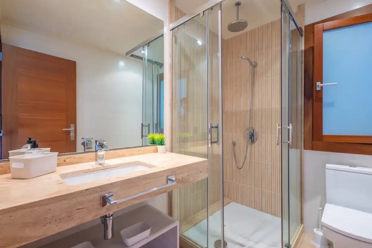 Un baño con un amplio lavabo y una ducha con mampara de vidrio.