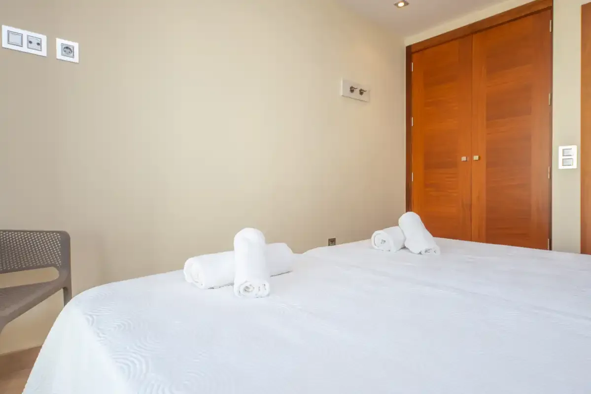 Un dormitorio con una cama bien tendida y puertas de armario de madera.