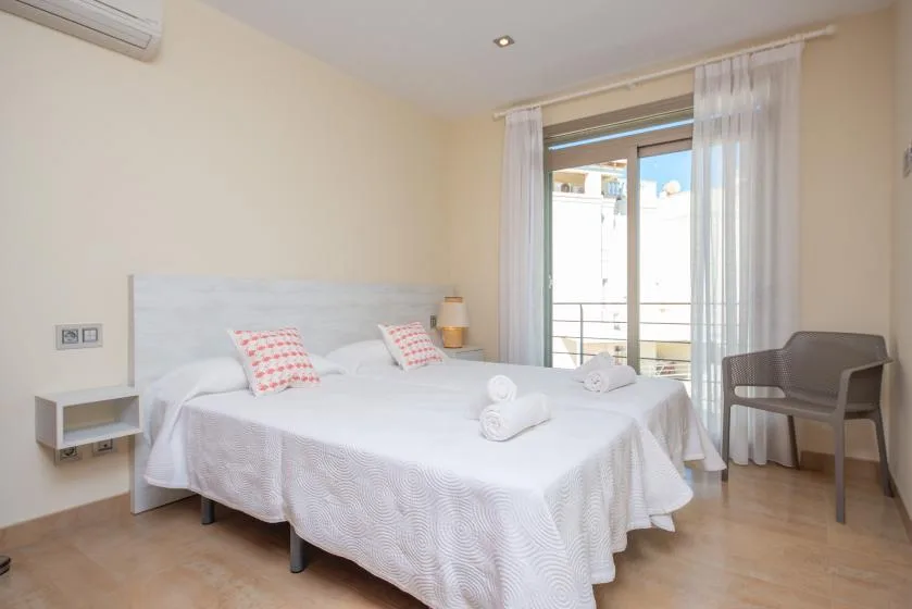 Un dormitorio luminoso con una cama bien hecha y cortinas junto a una puerta de cristal.