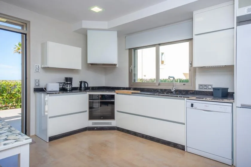 Una cocina moderna y luminosa con gabinetes blancos y encimeras oscuras.