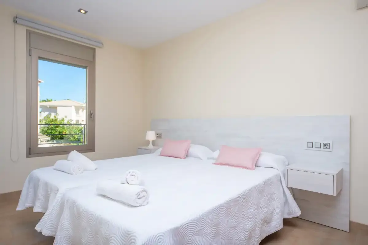 Un dormitorio luminoso con una cama grande y una ventana con vistas a la vegetación.