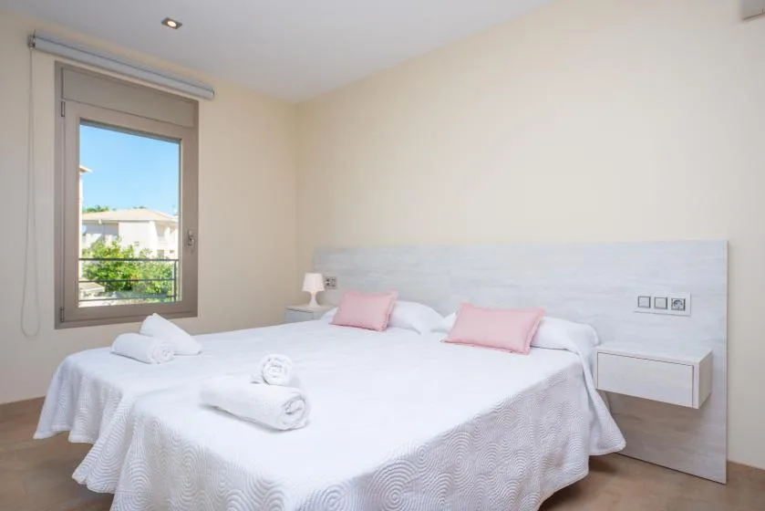 Un dormitorio luminoso con una cama bien arreglada y una ventana grande.