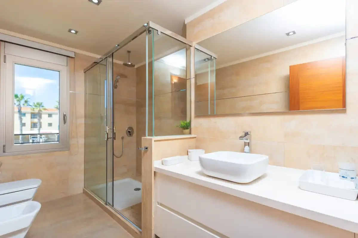 Un baño luminoso con una ducha de vidrio y un lavabo amplio.