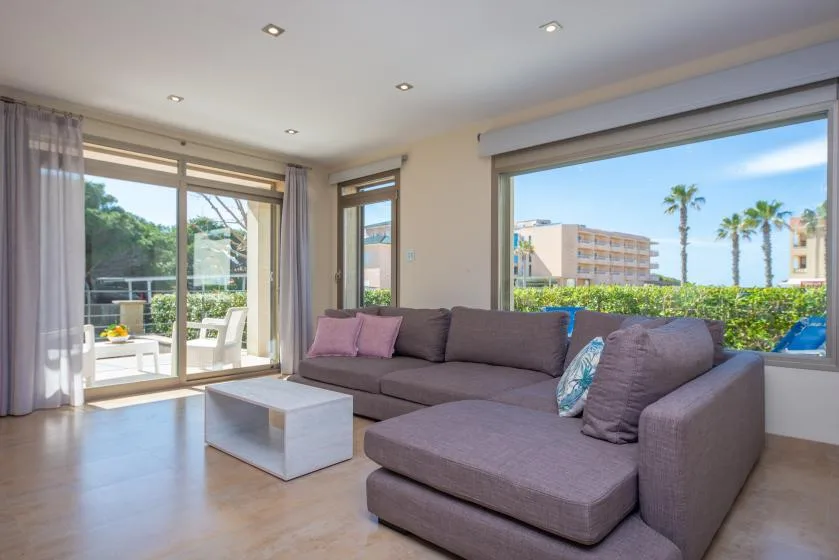 Una luminosa sala de estar con asientos seccionales junto a grandes ventanas y puertas corredizas de vidrio.