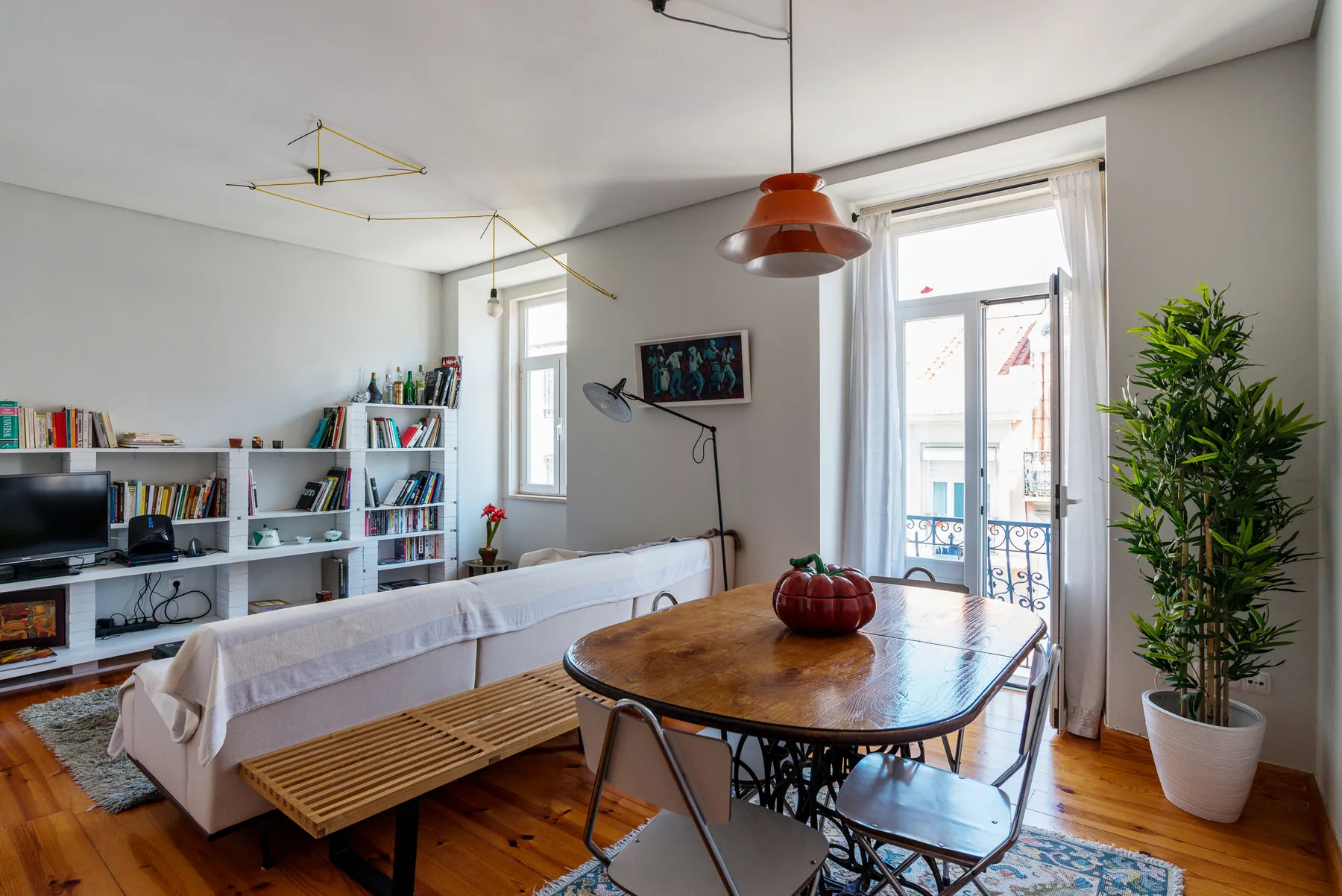 Sala de estar con asientos, una mesa de comedor y una luminosa puerta al balcón.