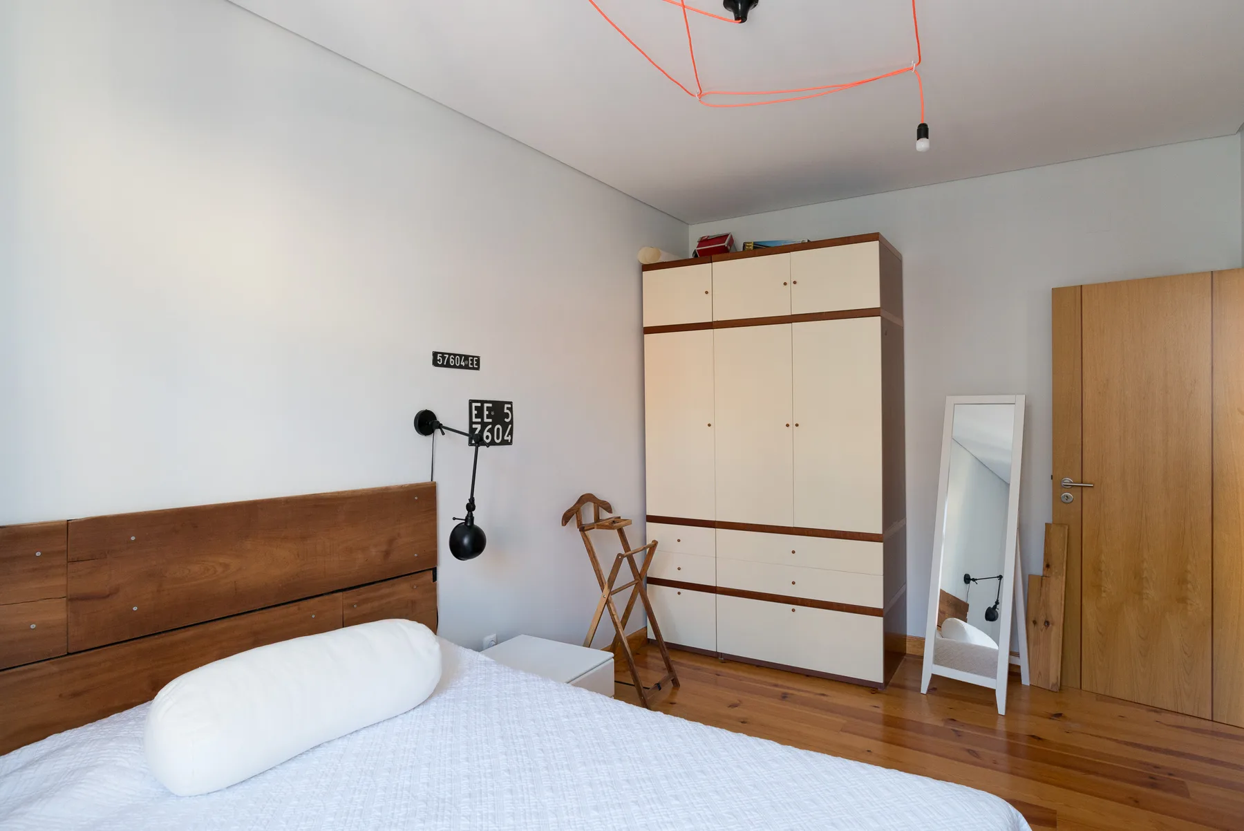 Un dormitorio con cama, armario y espejo junto a la puerta.