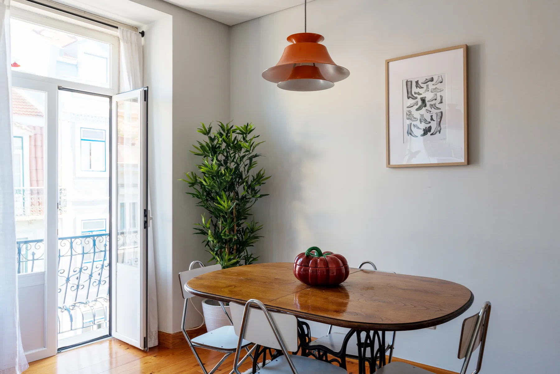 Un comedor con una mesa de madera, sillas y una planta en maceta.