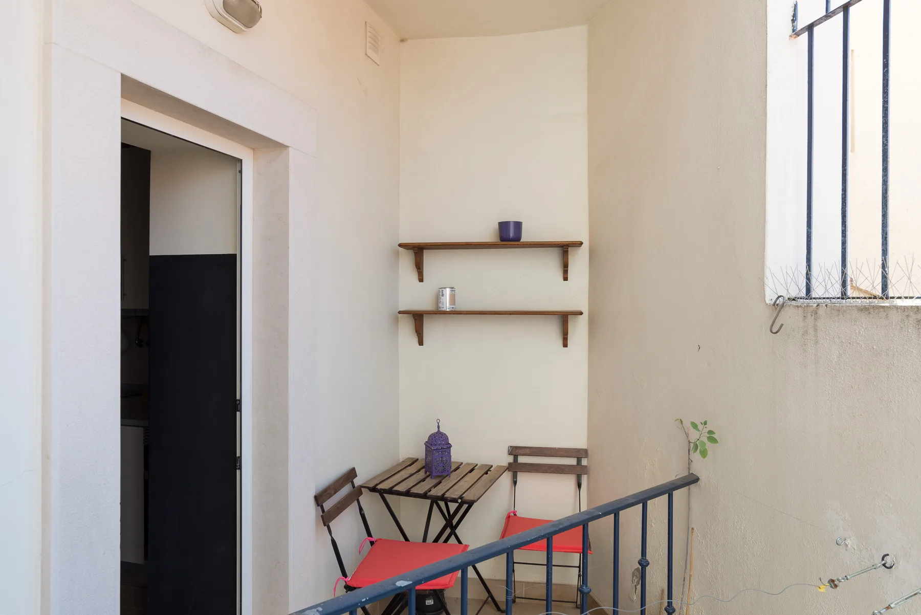 Una pequeña zona de comedor con una mesa y estantes junto a una pared blanca.