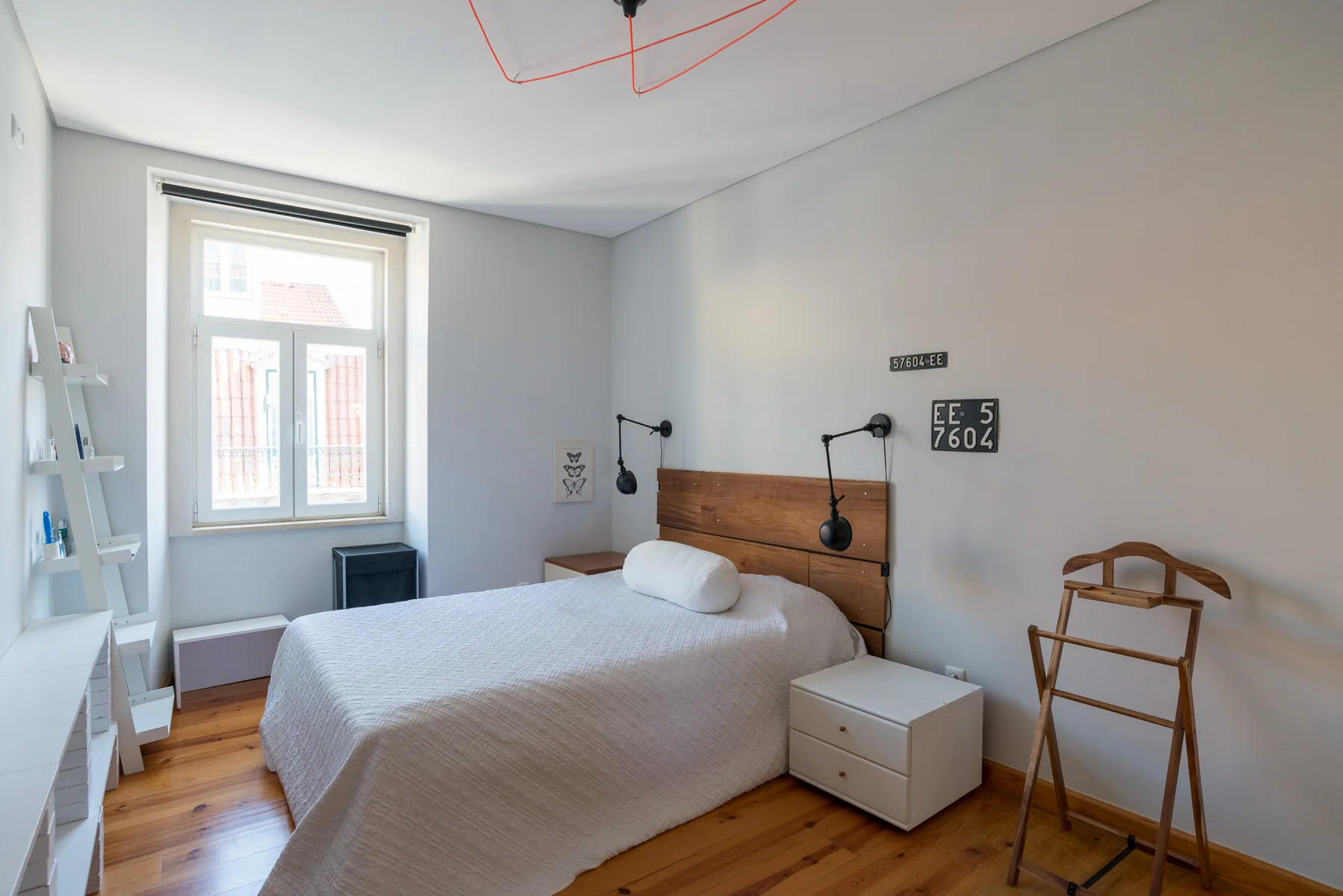 Un dormitorio con cama doble, mesitas de noche y una ventana alta.