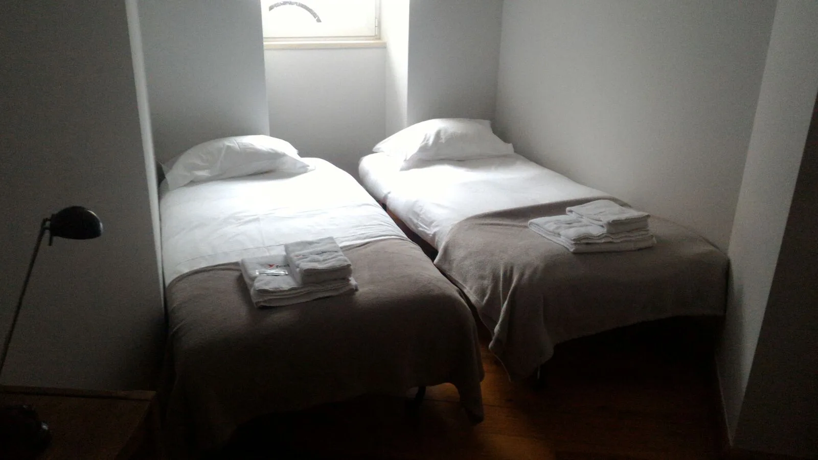 Un dormitorio pequeño con dos camas juntas bajo una ventana.