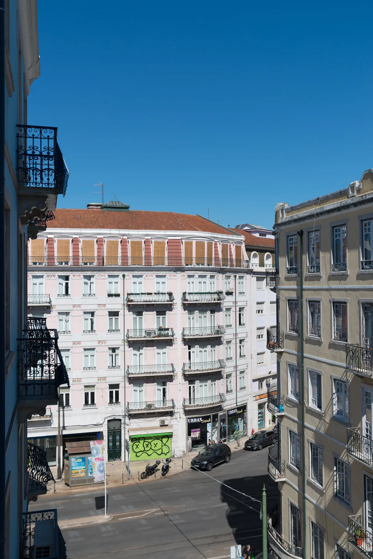 Escena callejera con edificios de varias plantas bajo un cielo azul despejado.