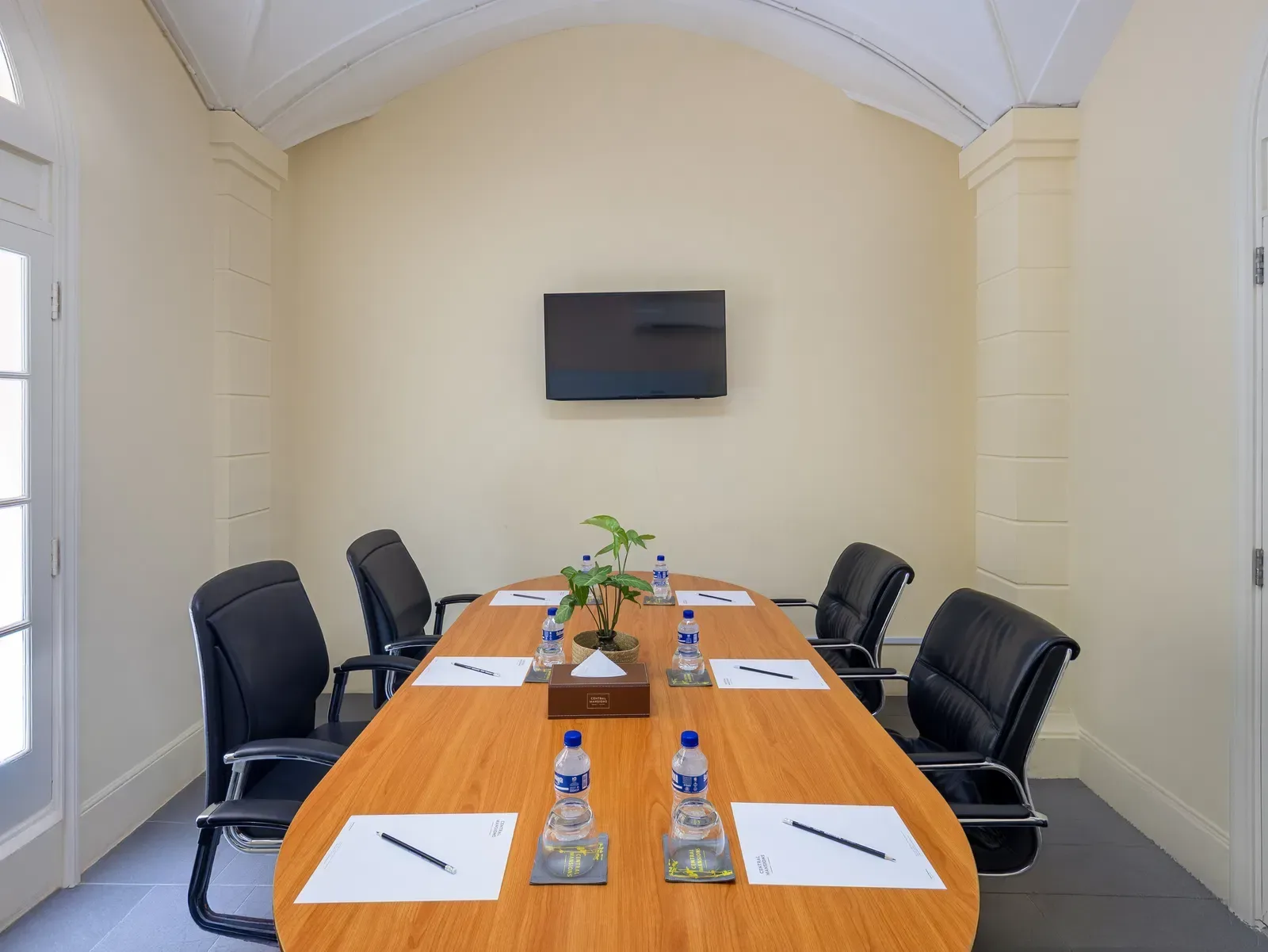 Sala de reuniones con mesa de conferencias y pantalla para presentaciones.