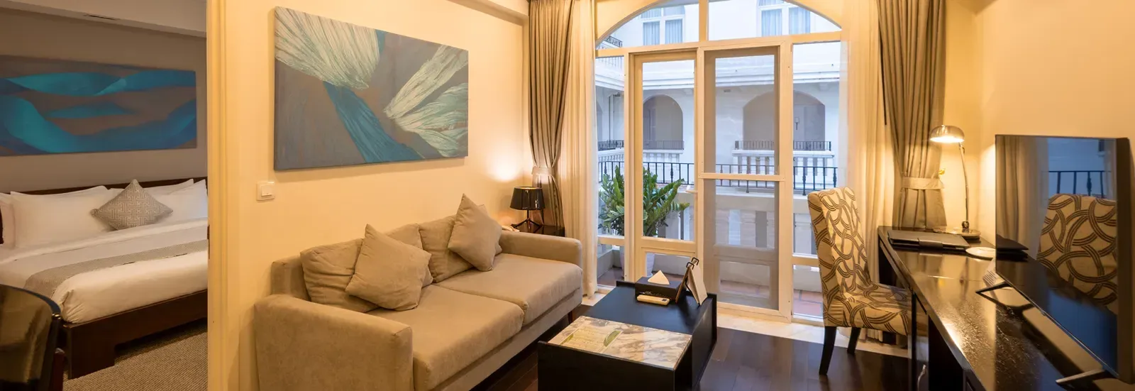 Two-bedroom family suite living area with sofa and large arched windows.
