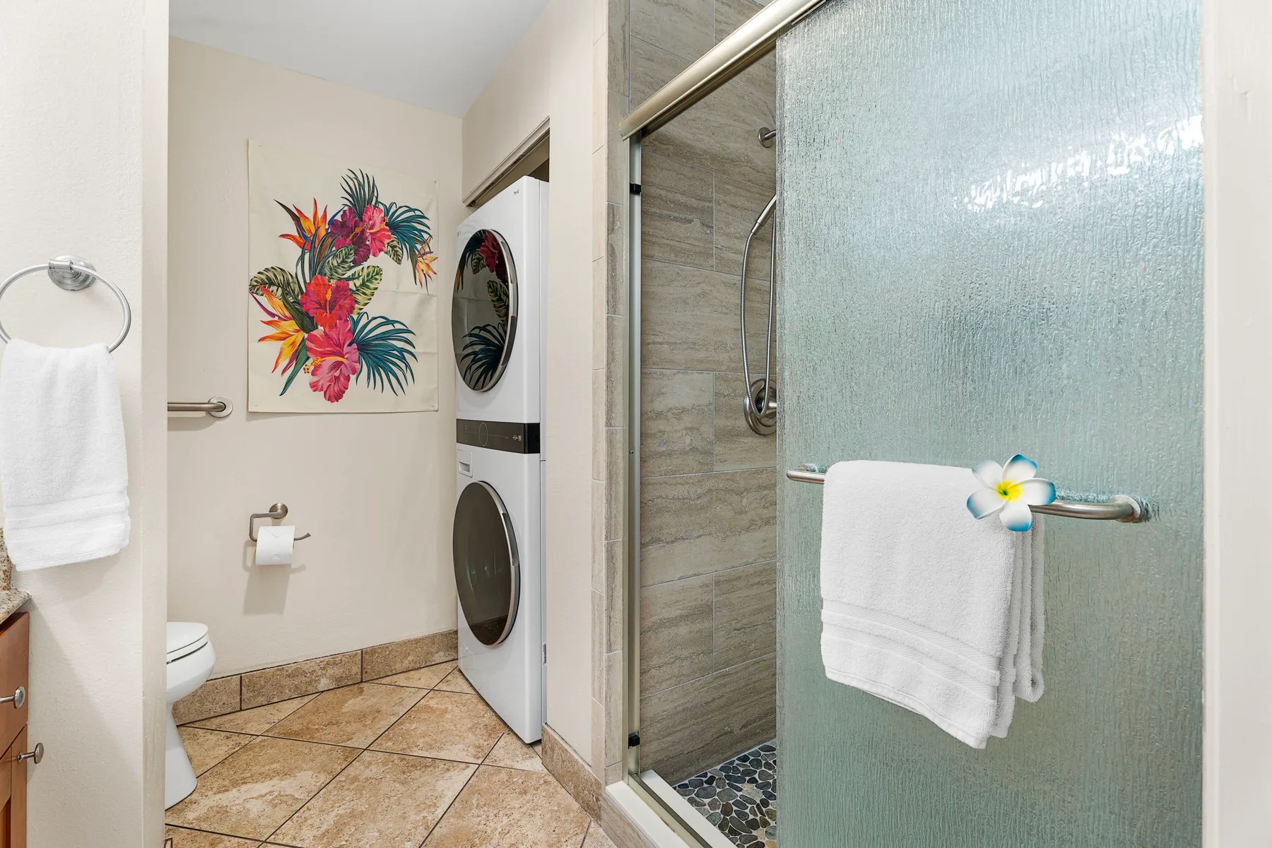 Un baño con ducha de vidrio, inodoro y una colorida obra floral.
