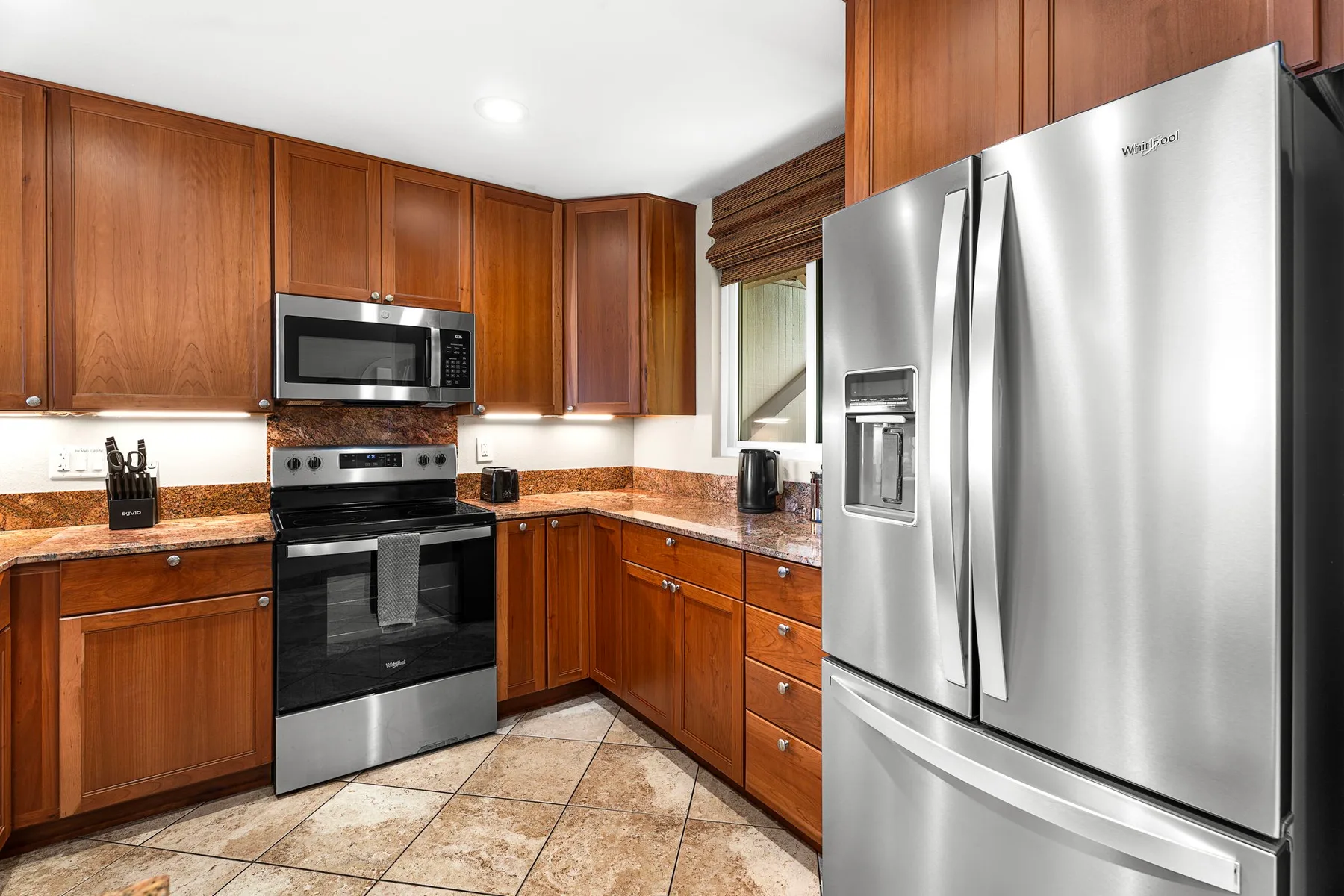 Una cocina con gabinetes de madera, una estufa y un refrigerador de acero inoxidable.