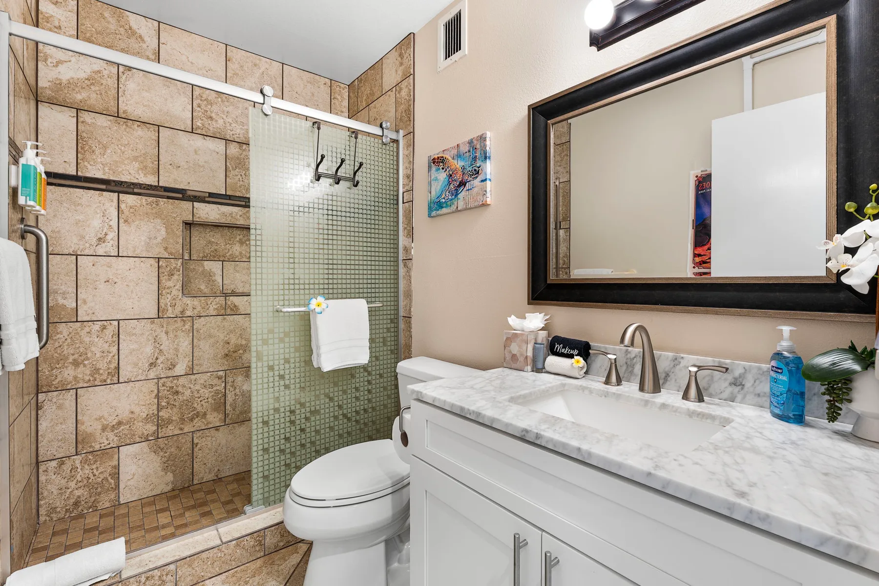 Un baño con ducha de vidrio, inodoro y tocador.