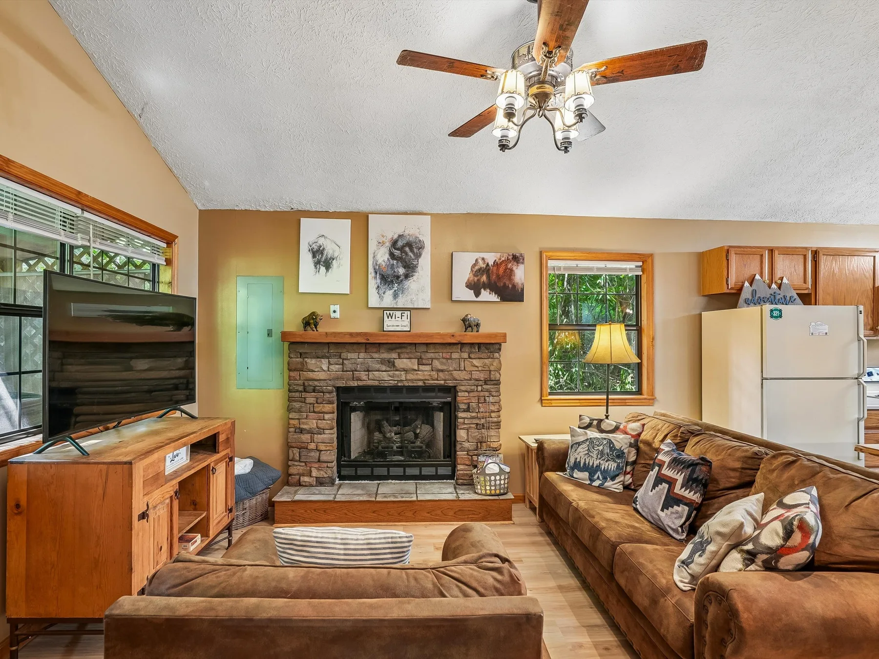 A living room with seating arranged around a brick fireplace and television.