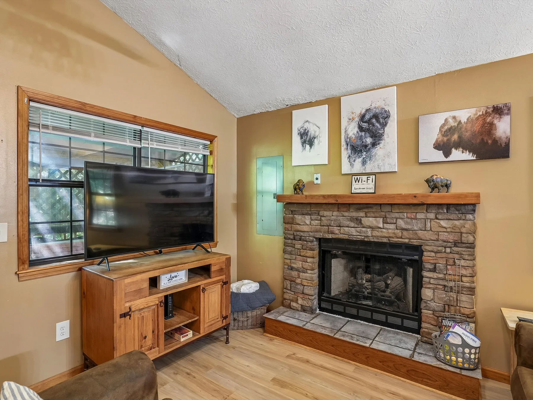 A living room with a television beside a stone fireplace.