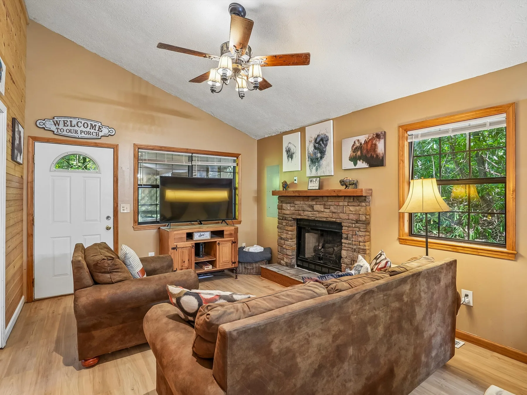 A living room with seating, a television, and a brick fireplace.