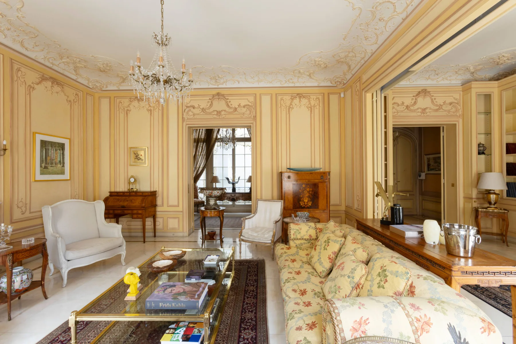 An ornate sitting room with patterned seating and a chandelier.