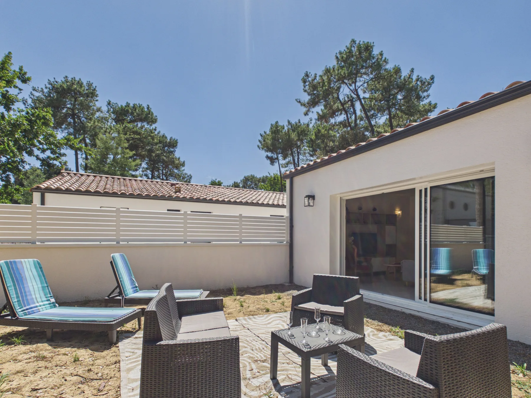 Outdoor patio with seating beside a house and sliding glass doors.