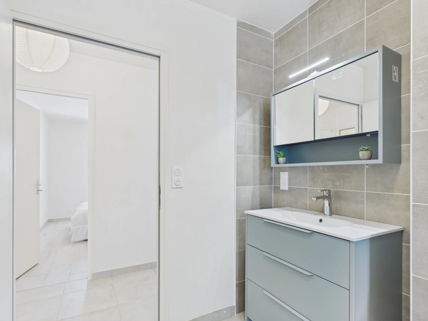 A bathroom with a sink vanity and mirrored cabinet.