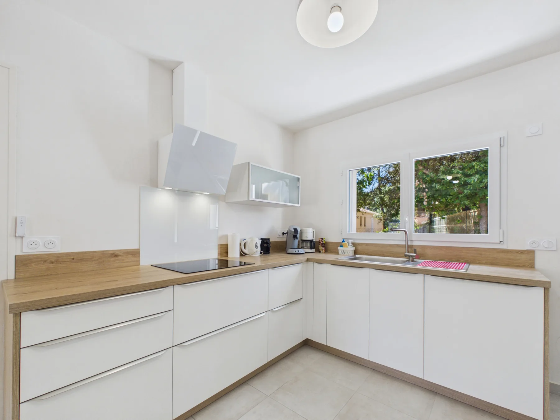 A bright kitchen with white cabinets and a wooden countertop.