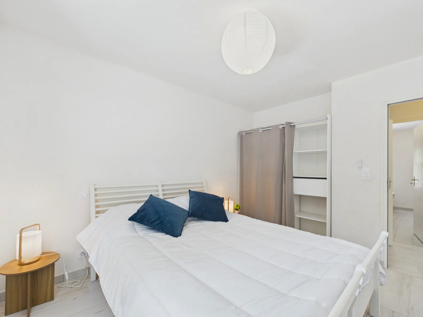 A bright bedroom with a white bed and dark blue pillows.