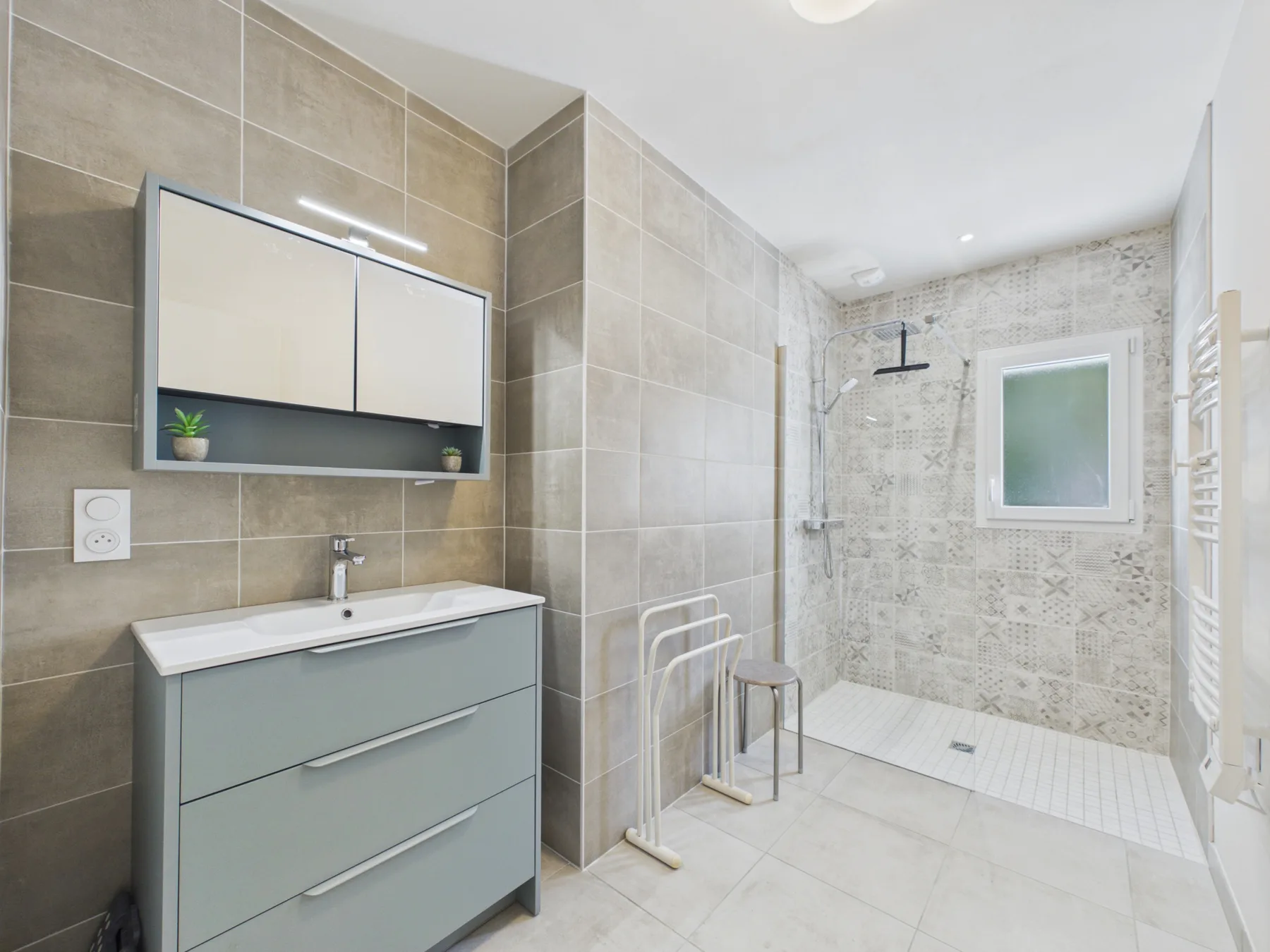 A tiled bathroom with a sink vanity and walk-in shower.