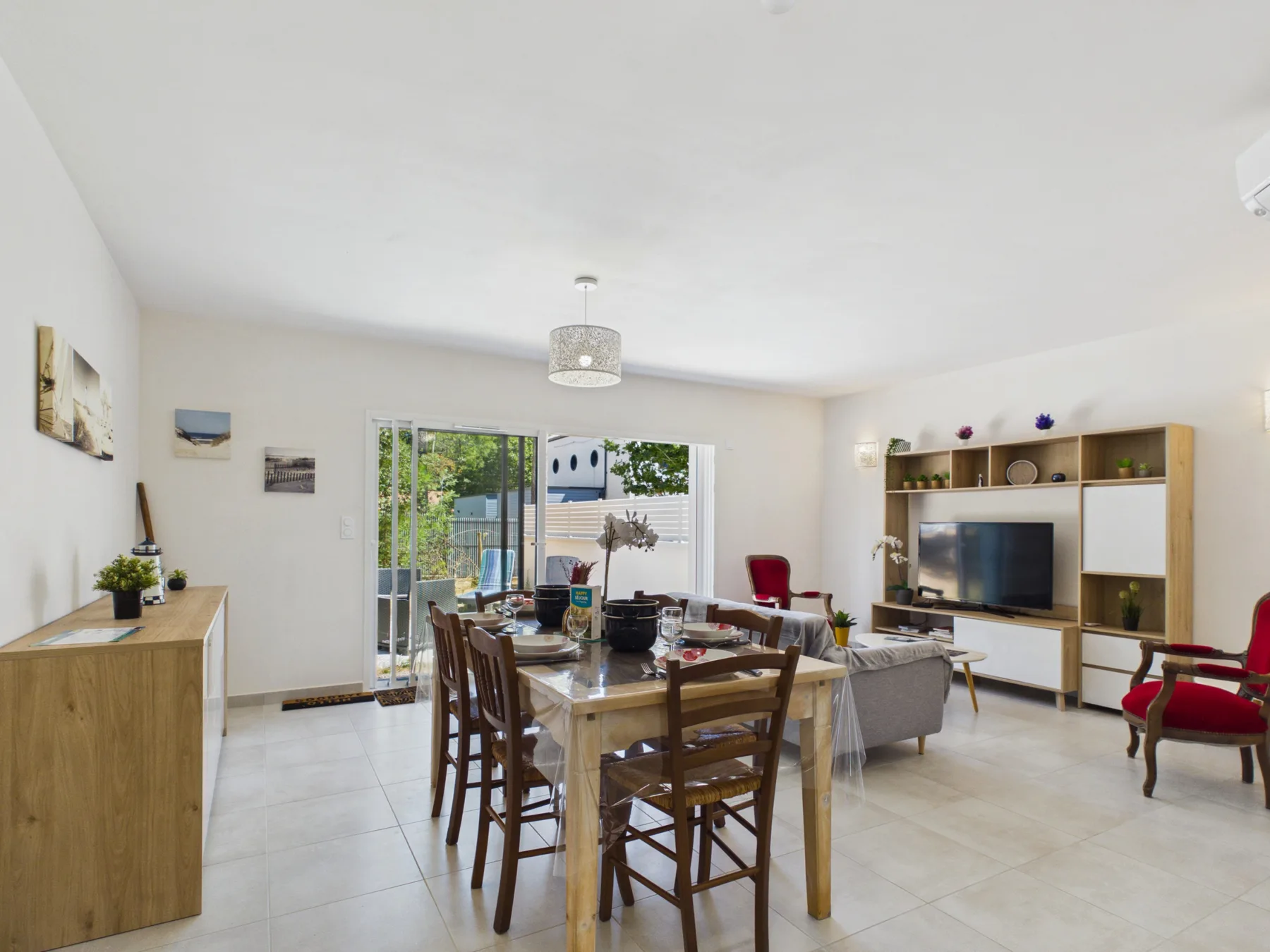A bright living and dining area with a table, seating, and a television.