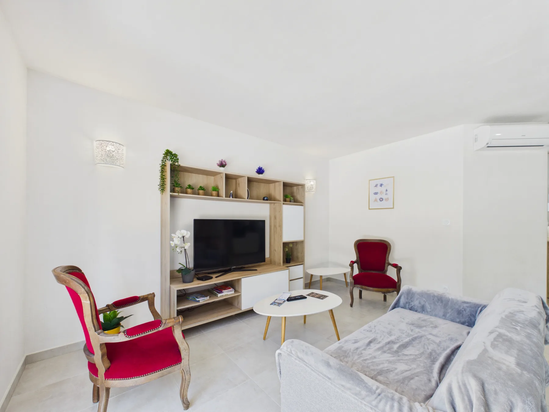 A bright living room with red accent seating and a television.