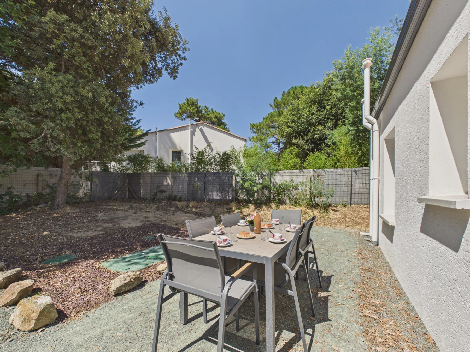 An outdoor dining area with a table and chairs beside the house.