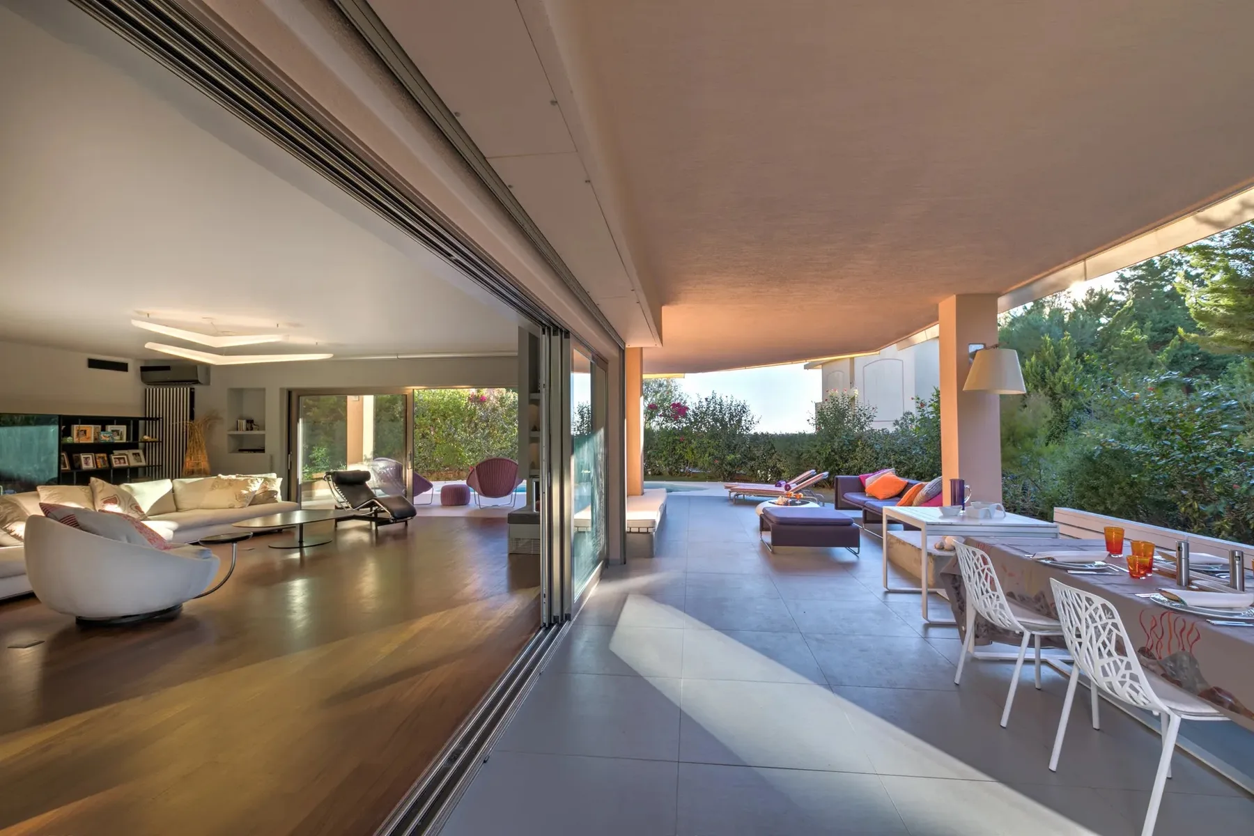 Una sala de estar y comedor se conecta con un patio cubierto y una piscina al fondo.