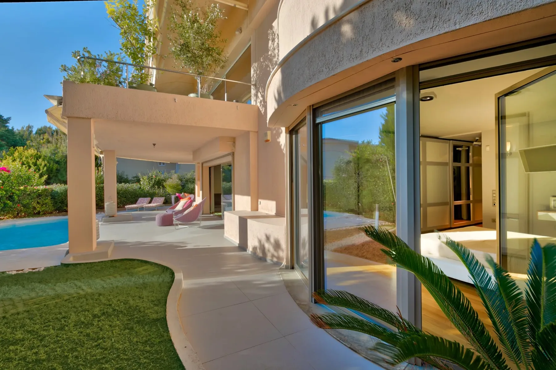 Un patio moderno se abre a una piscina junto a grandes puertas de vidrio.