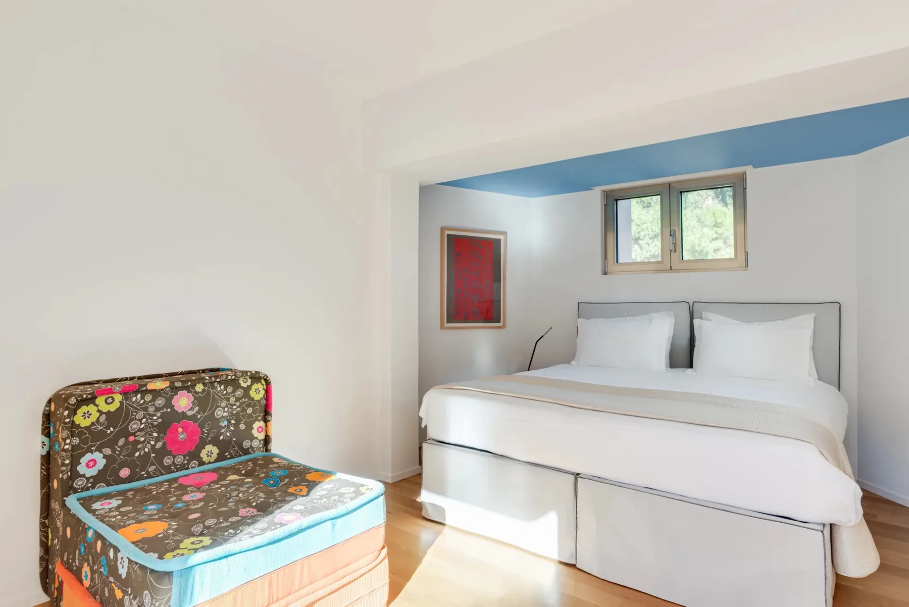 Un dormitorio con una cama y un asiento tapizado de colores.
