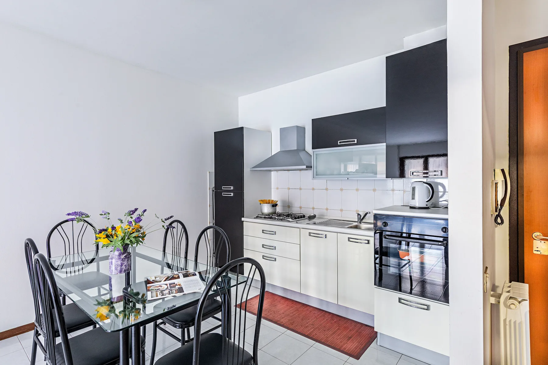 A bright kitchen with a glass dining table and metal-framed seating.