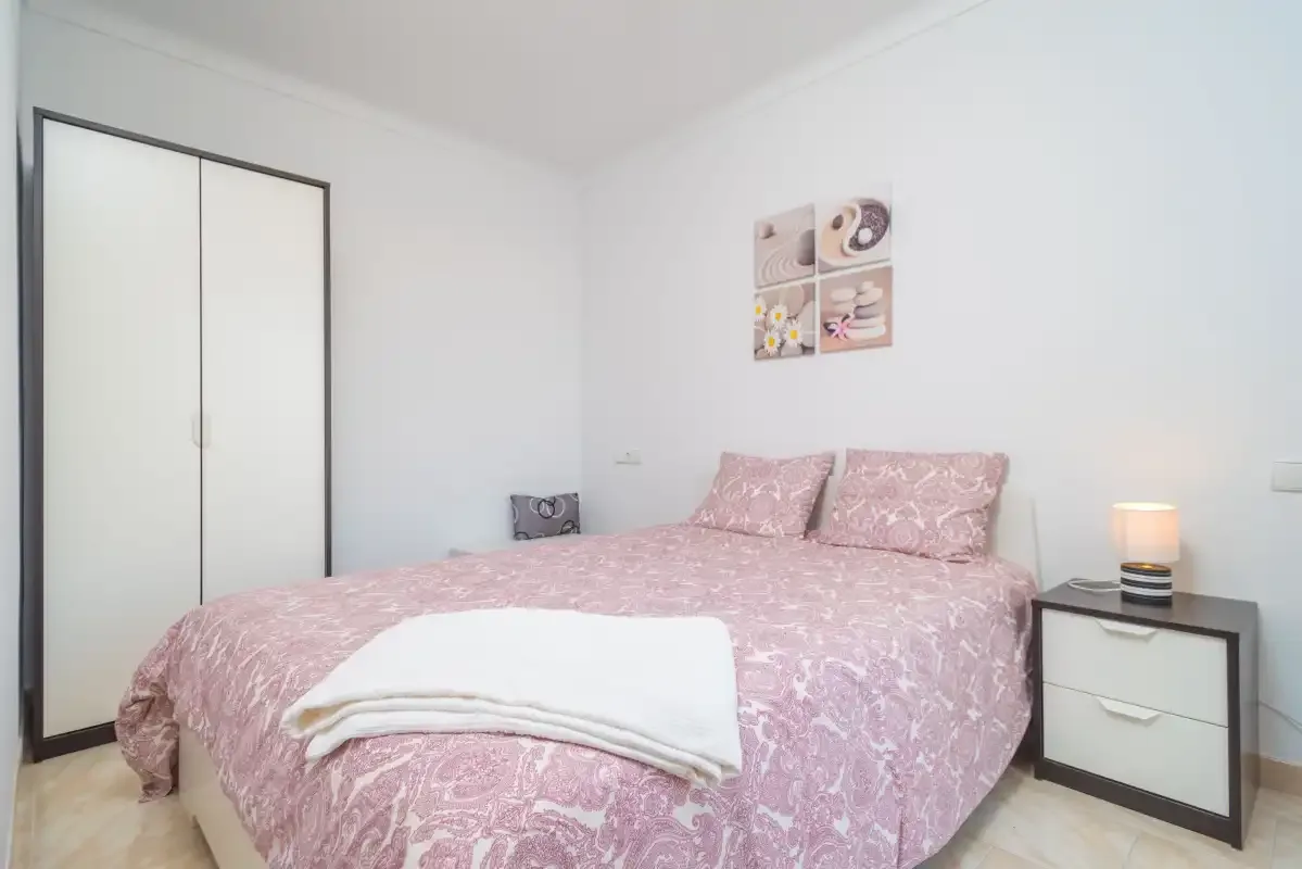 A bedroom with a pink bed and a wardrobe.