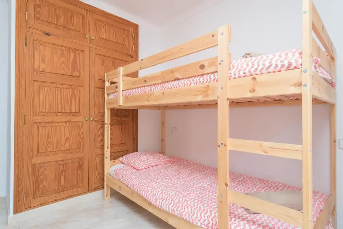 A bedroom with a wooden bunk bed and patterned bedding.