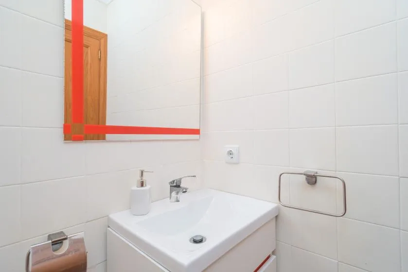 A tiled bathroom vanity with a sink, faucet, and wall mirror.